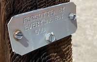 A grave marker that says: Forgotten by Everyone But God.